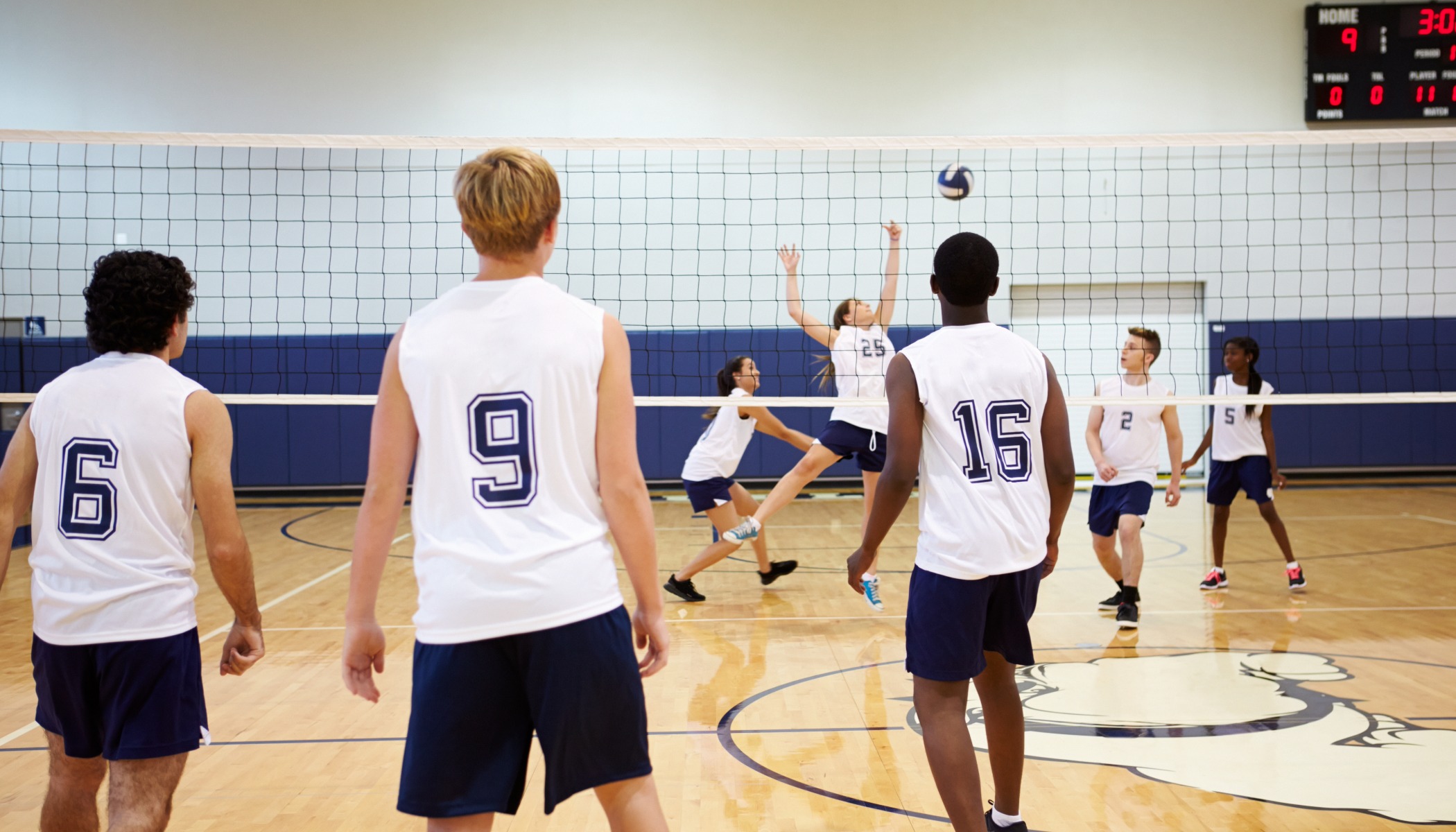 Men playing volleyball on an indoor court during a community sports event